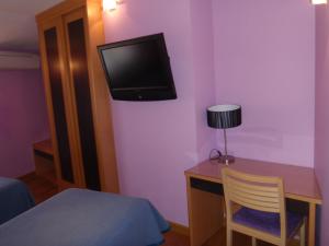 a bedroom with a desk and a tv on a purple wall at Hostal CC in Aranda de Duero