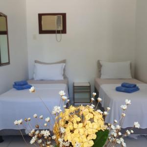 una camera con due letti e un vaso di fiori di Pousada Talismã a Florianópolis
