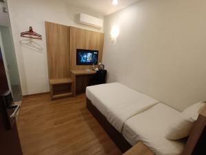 um quarto de hotel com uma cama e uma televisão em Greencity Hotel em Sungai Petani