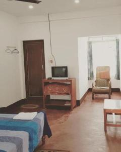 a bedroom with a bed and a tv and a chair at Bhaskar Homestay in Dibrugarh