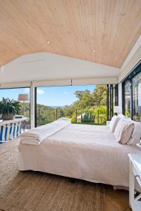 1 dormitorio con cama grande y ventana grande en The Outlook Cabana, en Terrigal