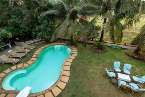 uma vista sobre uma piscina com cadeiras e palmeiras em Casa de Amor em Anjuna