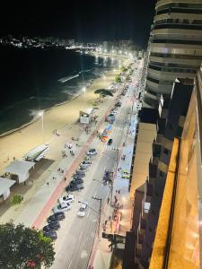 een straat met auto's die 's nachts op een strand geparkeerd staan bij praia do morro Guarapari,beira mar topíssimo apartamento in Guarapari
