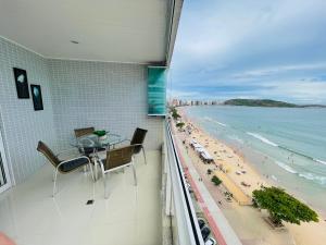 een balkon met een tafel en stoelen en het strand bij praia do morro Guarapari,beira mar topíssimo apartamento in Guarapari
