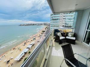 een balkon met stoelen en uitzicht op het strand bij praia do morro Guarapari,beira mar topíssimo apartamento in Guarapari