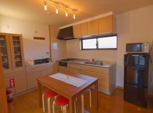a kitchen with a table and a sink and a refrigerator at ocean villa mint 海まで徒歩3分 水平線と星空を楽しむ一棟貸切オーシャンヴィラ in Chikura