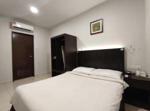 a bedroom with a large white bed with a black headboard at Hotel Desaru Penawar in Desaru
