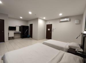 a hotel room with two beds and a television at Hotel Desaru Penawar in Desaru