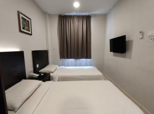a hotel room with two beds and a television at Hotel Desaru Penawar in Desaru