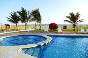 een zwembad met stoelen en palmbomen en de oceaan bij Luxury House 11 Private Beach 45Min Guayaquil in Salinas