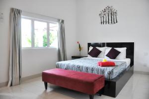 a bedroom with a bed and a red bench at Langkawi Chantique in Pantai Cenang
