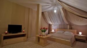 sypialnia z łóżkiem, telewizorem i kwiatami w obiekcie Hotel Hibiskus w mieście Boguchwała