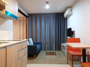 4 Floor - Centrio Condominium near Shopping Malls and Andamanda Water Park في فوكيت تاون: غرفة معيشة مع أريكة زرقاء ومطبخ