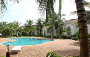 a swimming pool in front of a house with palm trees at Luxury Stay at GOA in Anjuna