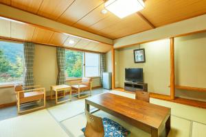 a living room with a wooden table and a television at KAMENOI HOTEL Shiobara in Nasushiobara