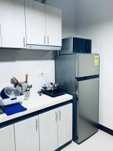 Una cocina con gabinetes blancos y un refrigerador de acero inoxidable. en Angel's Nest, en Lo-oc