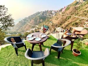 a table and chairs on the grass with a mountain at Vanshika homes Near mall road in Kasauli