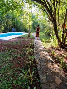 uma pessoa a caminhar por um caminho de pedra ao lado de uma piscina em Cabaña Oma em Puerto Iguazú
