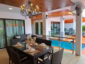 ein Esszimmer mit einem Tisch, Stühlen und einem Pool in der Unterkunft The Chic Pool Villa in Nai Yang Beach
