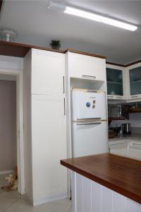 cocina con armarios blancos y nevera blanca en Apartamento aconchegante em Floripa - caminho das praias, en Florianópolis