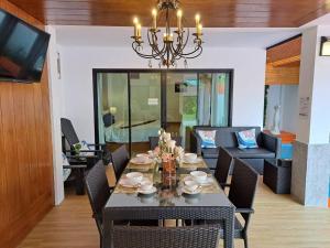 uma sala de jantar com uma mesa com cadeiras e um lustre em The Chic Pool Villa em Nai Yang Beach