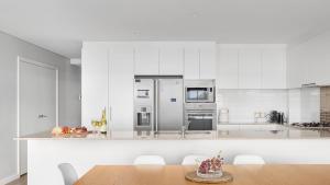 a kitchen with white walls and a wooden table at Solaris in Fingal Bay