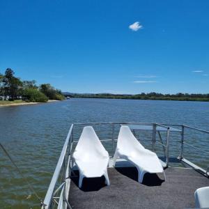 two white chairs sitting on the end of a boat at The one & only Houseboat Hire on Maroochy River in Maroochydore