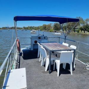 einen Tisch und Stühle auf einem Boot im Wasser in der Unterkunft The one & only Houseboat Hire on Maroochy River in Maroochydore