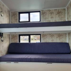 a bed in a room with two windows at The one & only Houseboat Hire on Maroochy River in Maroochydore