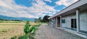 a house with a gravel road next to a field at Blessing Pua in Ban Lao