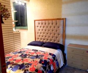 a bedroom with a bed with a floral bedspread at La Terraza del Pochote in Oaxaca City