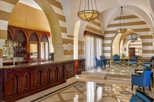 a lobby with a bar with blue chairs at Jaz Lamaya Resort in Coraya Bay