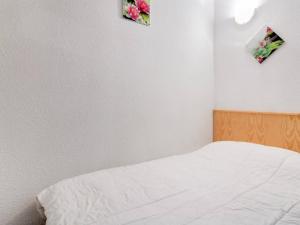 Esquièze - SèreにあるAppartement Esquièze-Sère, 2 pièces, 4 personnes - FR-1-402-21の白いベッド1台と壁に2枚の絵が飾られたベッドルーム1室が備わります。