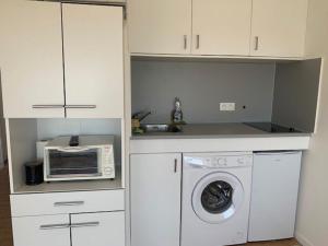 eine Küche mit einer Waschmaschine und einer Mikrowelle in der Unterkunft Studio Cap d'Agde, 1 pièce, 4 personnes - FR-1-607-71 in Cap d'Agde