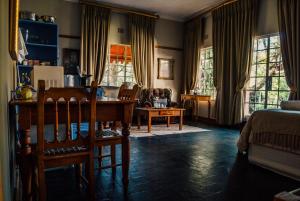 - un salon avec une table, des chaises et des fenêtres dans l'établissement Farm stay at Saffron Cottage on Haldon Estate, à Bloemfontein