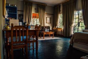 a living room with a table and chairs and windows at Farm stay at Saffron Cottage on Haldon Estate in Bloemfontein