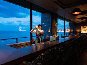 un homme debout au bar avec un verre dans l'établissement Grandvrio Hotel Beppuwan Wakura - ROUTE INN HOTELS -, à Beppu