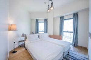 ein Schlafzimmer mit einem großen weißen Bett und einem Fenster in der Unterkunft Expo Village Serviced Apartments in Dubai