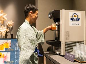 a man standing in front of a coffee machine at Grandvrio Hotel Beppuwan Wakura - ROUTE INN HOTELS - in Beppu