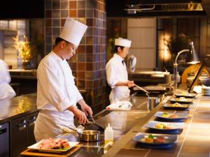 dwóch kucharzy stojących w kuchni przygotowujących jedzenie w obiekcie Grandvrio Hotel Beppuwan Wakura - ROUTE INN HOTELS - w mieście Beppu