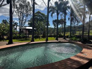 a swimming pool with palm trees around it at Coolangatta Estate Shoalhaven Heads in Berry