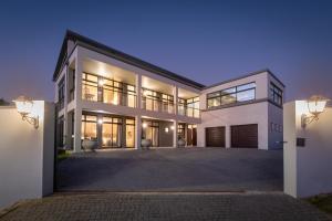 a large house with a driveway at night at Anchor's Haven Hersham in Groot Brak Rivier