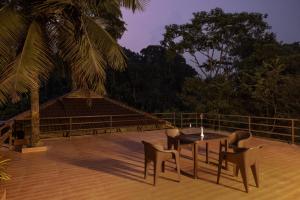 a patio with a table and chairs on a deck at Avadale Thekkady - Stag Groups Not Allowed in Thekkady