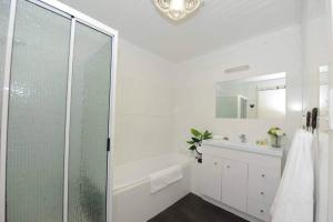 a white bathroom with a shower and a sink at White Shell Cottage - Woodfire & Beachfront in Falmouth