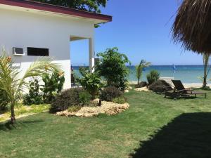 a yard with chairs and the ocean in the background at BambooBeachVilla2 AC NEW OCEANFRONT POOL sunsetview garden kitchen SATELLITE STARLINK WI-FI in Dimiao