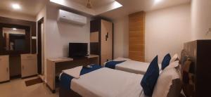 a hotel room with two beds and a television at Hotel Kosala Vijayawada in Vijayawāda
