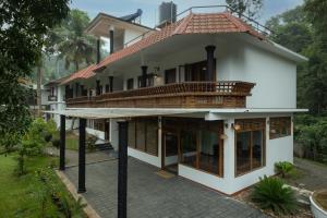 a house with a balcony on top of it at Avadale Thekkady - Stag Groups Not Allowed in Thekkady