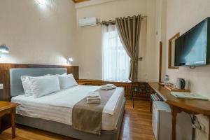 a bedroom with a bed and a desk and a television at Hotel Malika Bukhara in Bukhara