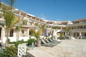 un hotel con sillas y sombrillas en un patio en Aphrodite Sands Resort complex has a sauna, fitness room, health spa, jacuzzis en Mandria