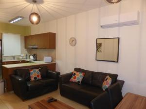 een woonkamer met 2 leren banken en een keuken bij Aphrodite Sands Resort complex has a sauna, fitness room, health spa, jacuzzis in Mandria